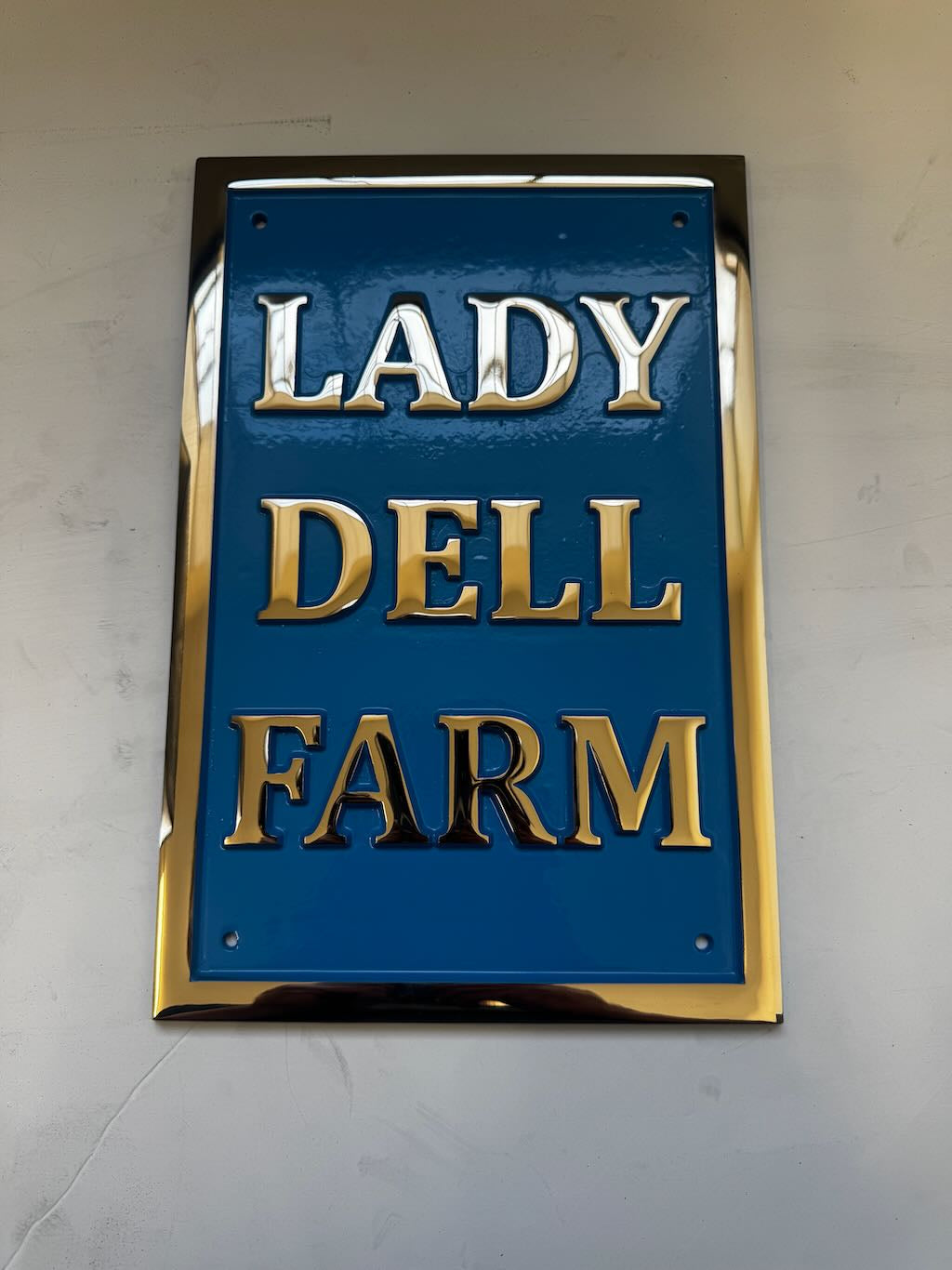 Decorative sign with 'LADY DELL FARM' text on a blue background with gold lettering.