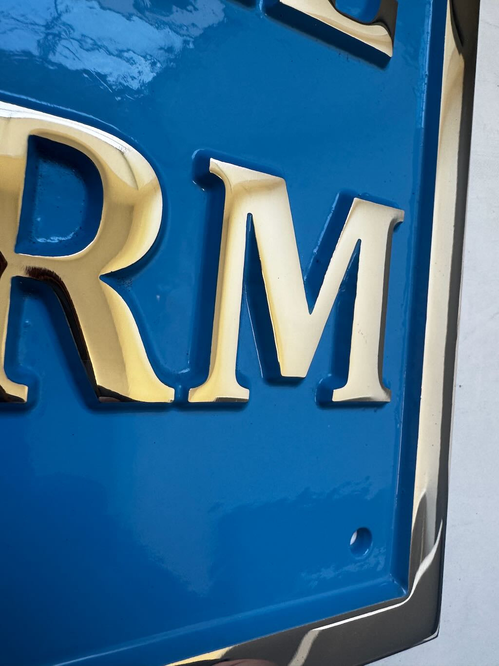 Close-up of a blue sign with gold letters 'RM' on a white background