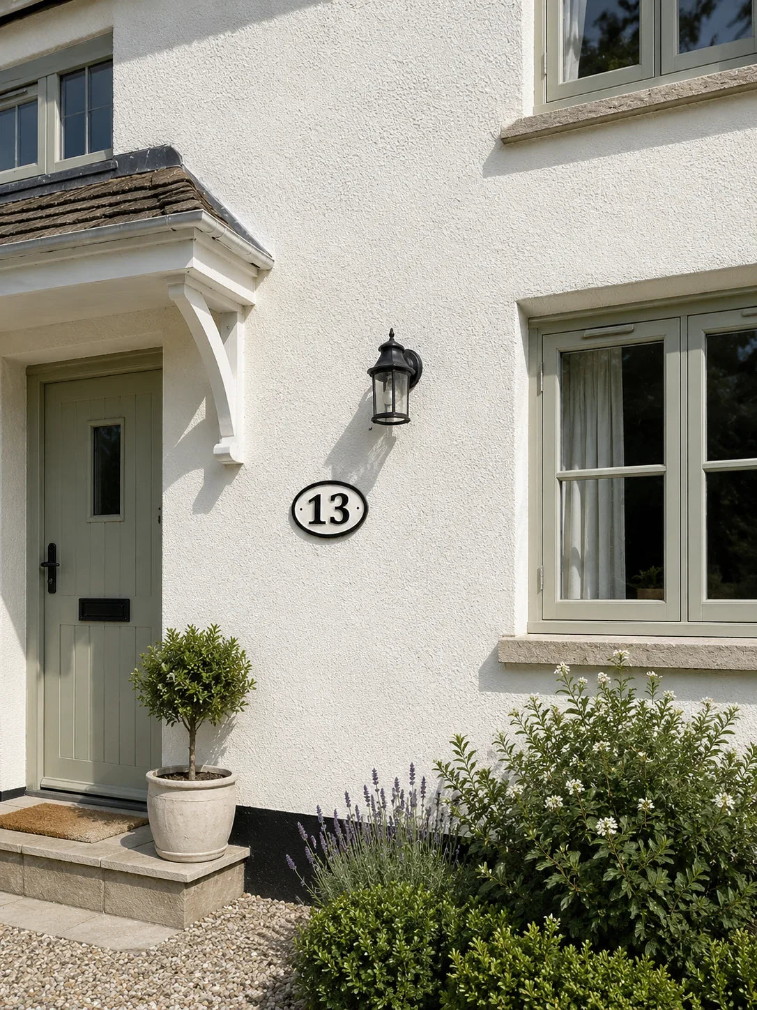 White rendered house exterior with grey windows and front door.