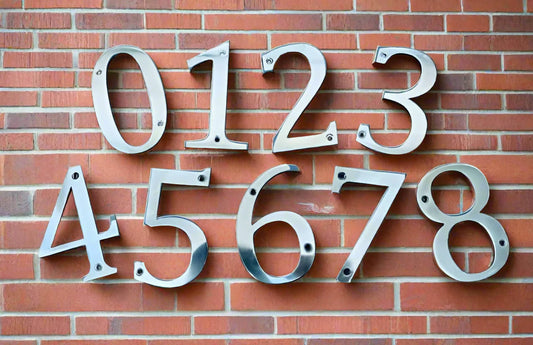 Metal house numbers displayed on a brick wall