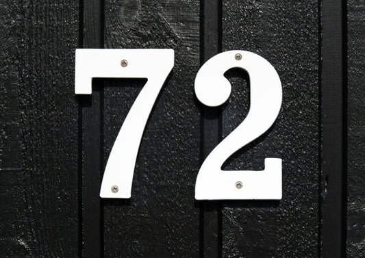 White house number 72 mounted on black wooden wall