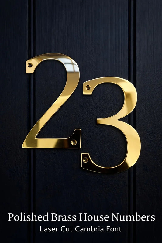 Polished brass house number 23 in Cambria font mounted on a black front door