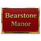 A rectangular red plaque with raised gold lettering reading 'Bearstone Manor' and a polished gold border, shown on a white background.