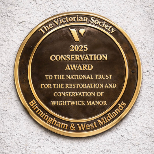 Cast bronze circular heritage plaque with raised lettering mounted on exterior wall
