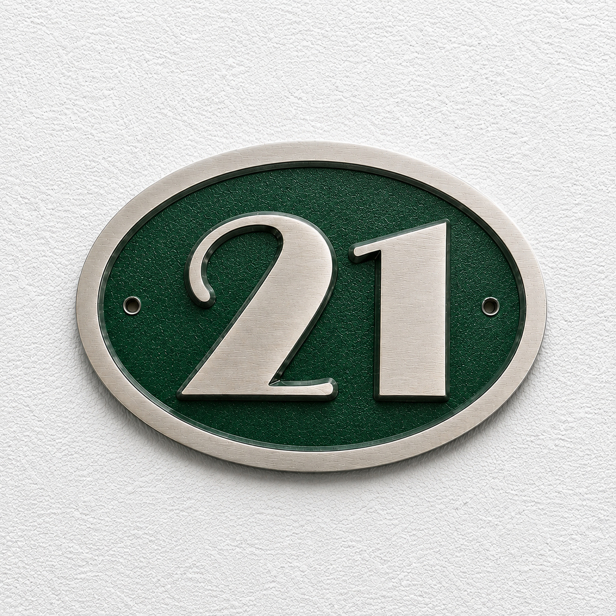 An oval house number plaque featuring the number 21 in brushed silver metal over a textured dark green background, mounted on a white textured wall.