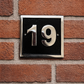 Cast aluminium square house number sign with raised polished numerals black background and background fixing holes