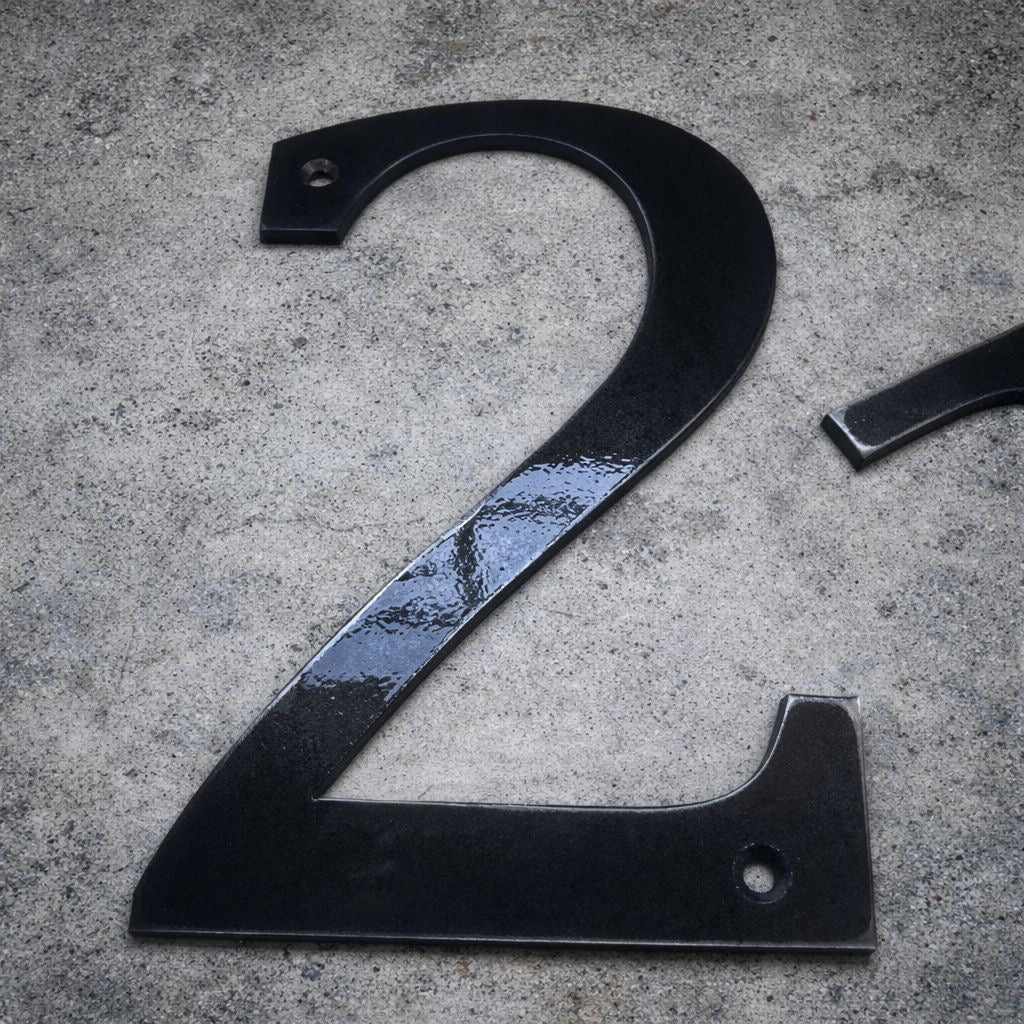 Black metal number '2' on a textured gray surface