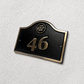 Cast bronze hotel room number sign with custom logo and raised numbers mounted on wall