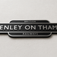 A black metal sign reading 'HENLEY ON THAMES RAILWAYS' with silver lettering, mounted on a light textured wall. Small text on the left indicates 10mm depth.