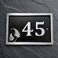 Personalised cast aluminium house number plaque featuring satin-finished number 45 with decorative fern motif and black textured background.
