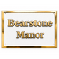 A rectangular white plaque or sign with a polished gold border and raised gold lettering that reads 'Bearstone Manor' on a white background.