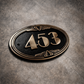 Cast bronze oval house number sign with Art Deco border and raised polished numerals on exterior wall