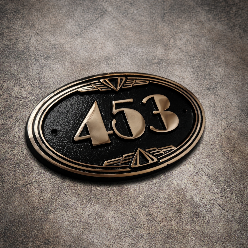 Cast bronze oval house number sign with Art Deco border and raised polished numerals on exterior wall