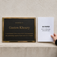 A memorial plaque with a black background and gold border next to a hand holding a sheet of white A4 paper, set against a textured beige wall.