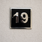 Cast aluminium square house number sign with raised polished numerals black background and background fixing holes