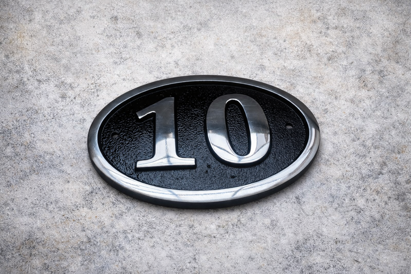 Cast aluminium oval hotel room number sign with raised numbers and black background mounted on wall