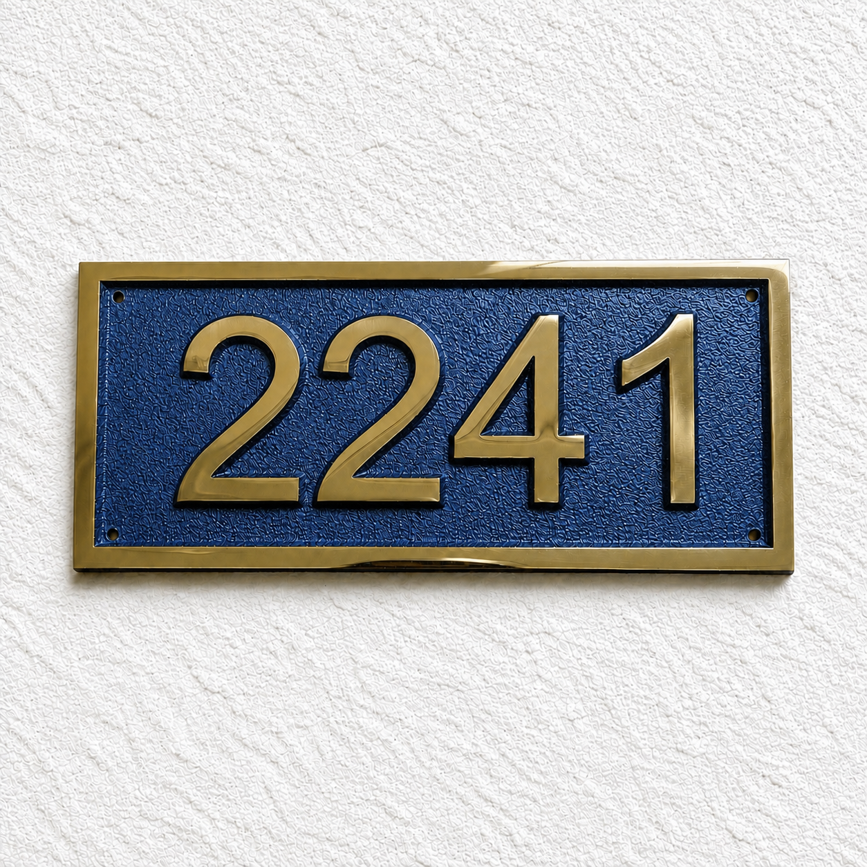 A rectangular house number plaque with raised gold numerals '2241' on a textured dark blue background, mounted on a white textured wall.