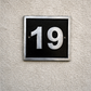 Cast aluminium square house number sign with raised satin numerals black background and background fixing holes