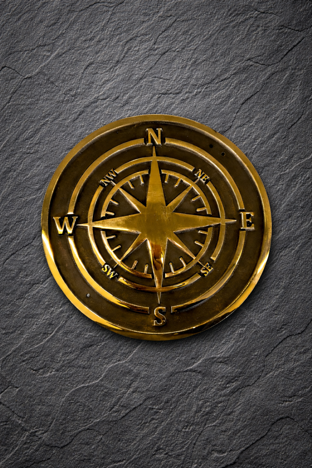 Cast bronze compass wall plaque with raised compass rose detail mounted on exterior wall