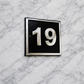 Cast aluminium square house number sign with raised polished numerals black background and background fixing holes