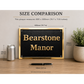A black rectangular plaque with gold lettering reading 'Bearstone Manor' is shown on a tabletop with overlaid size measurements comparing it to a soda can and pen. The image includes the text 'SIZE COMPARISON' and dimensions for the plaque.