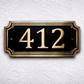 Cast bronze rectangle house number sign with raised numbers and double border mounted on exterior wall