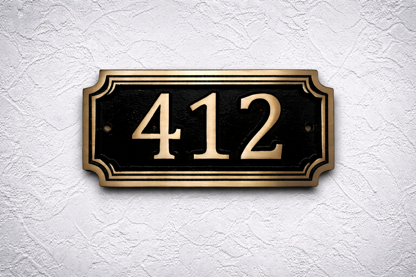 Cast bronze rectangle house number sign with raised numbers and double border mounted on exterior wall