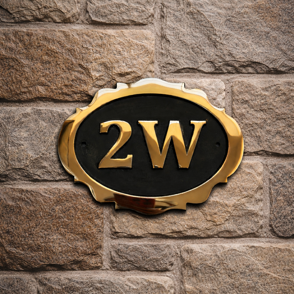 Cast bronze oval house number sign with decorative edge and raised lettering mounted on stone wall

