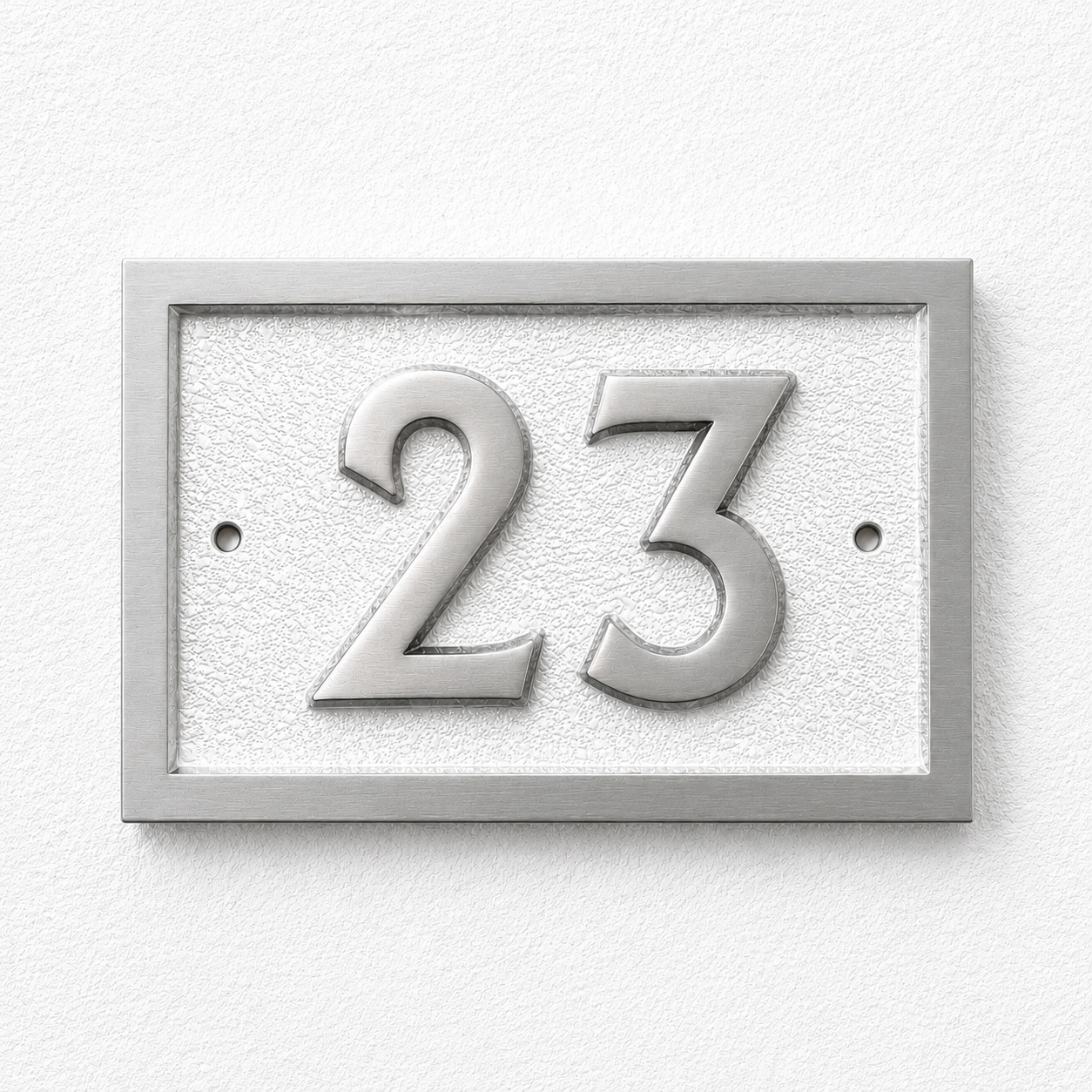 A rectangular house number plaque displaying '23' in raised metallic numerals on a textured light background, mounted on a white wall.