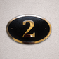 Cast bronze oval house number sign with polished raised numeral and black background
