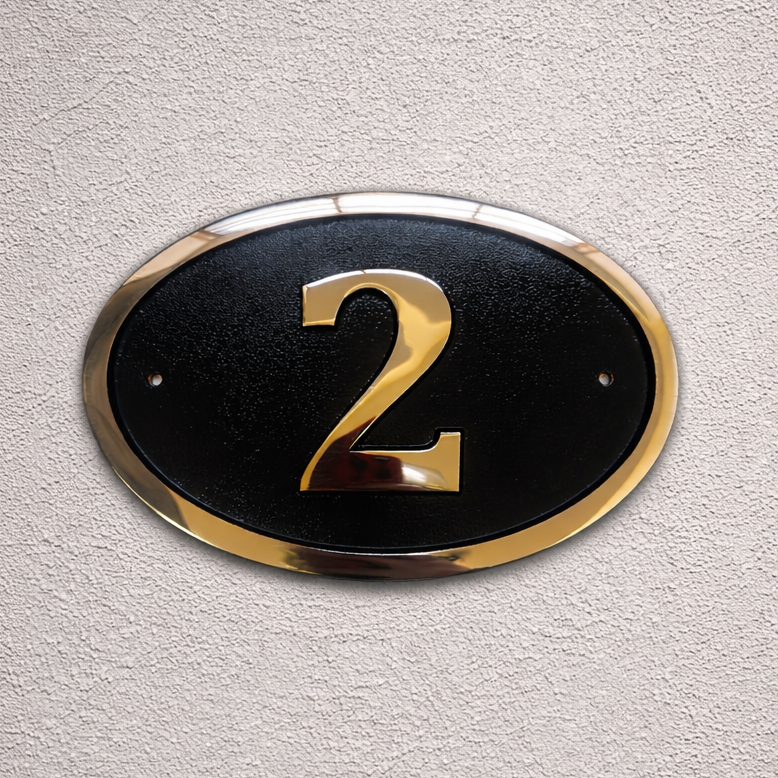 Cast bronze oval house number sign with polished raised numeral and black background
