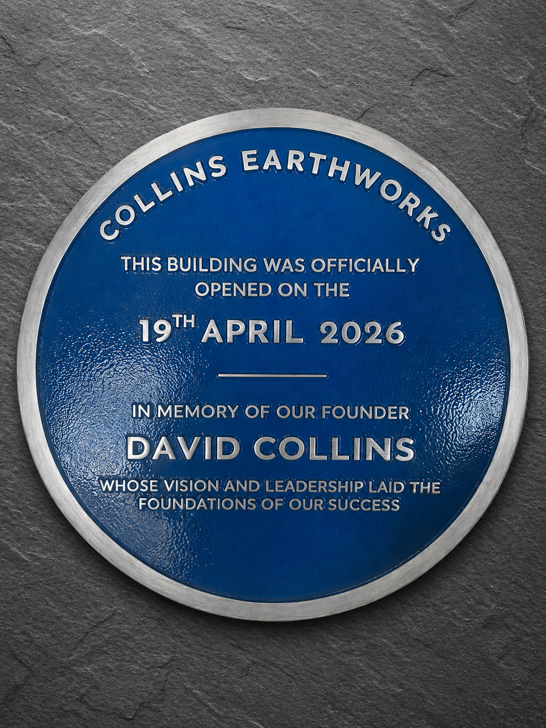 Modern blue heritage plaque with brushed silver border and raised lettering mounted on exterior wall