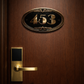 Cast bronze oval house number sign with Art Deco border and raised polished numerals on exterior wall
