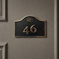 Cast bronze hotel room number sign with custom logo and raised numbers mounted on wall