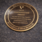 Cast bronze circular heritage plaque with raised lettering mounted on exterior wall