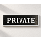 A rectangular black sign with a white border and the word 'PRIVATE' in large white serif letters, mounted on a textured white wall.