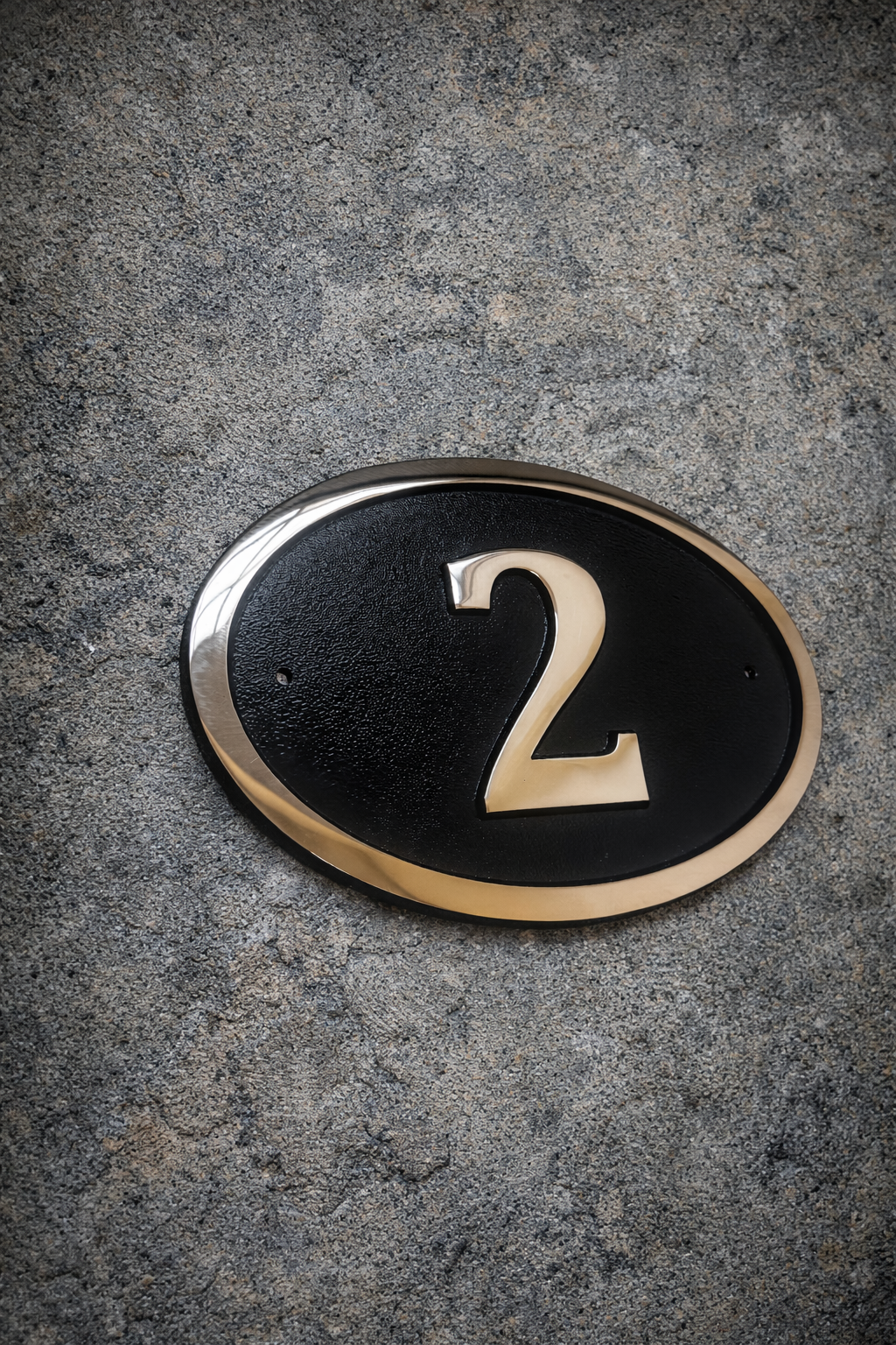 Cast bronze oval house number sign with polished raised numeral and black background
