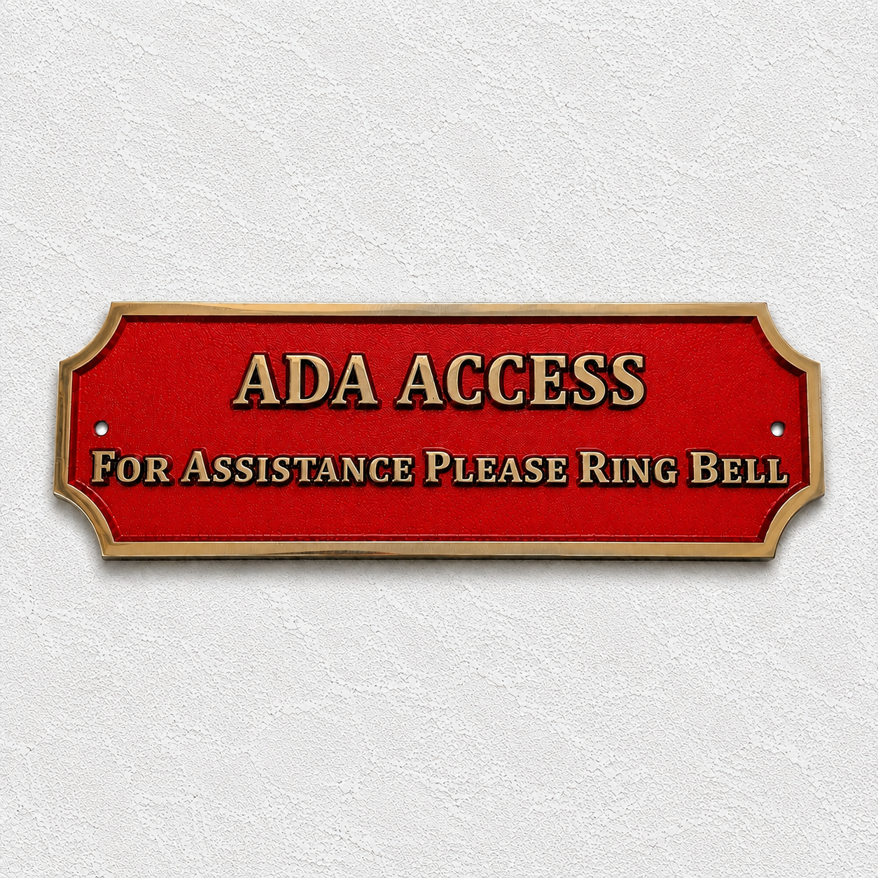 A red ADA Access sign with gold lettering and a gold border, mounted on a textured white wall. The sign reads 'ADA ACCESS' and 'FOR ASSISTANCE PLEASE RING BELL'.
