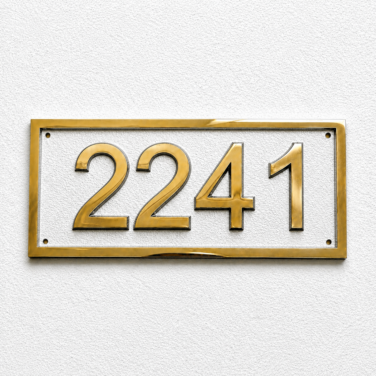 Gold house number plaque displaying '2241' in raised numerals on a white rectangular background, mounted on a textured white wall.