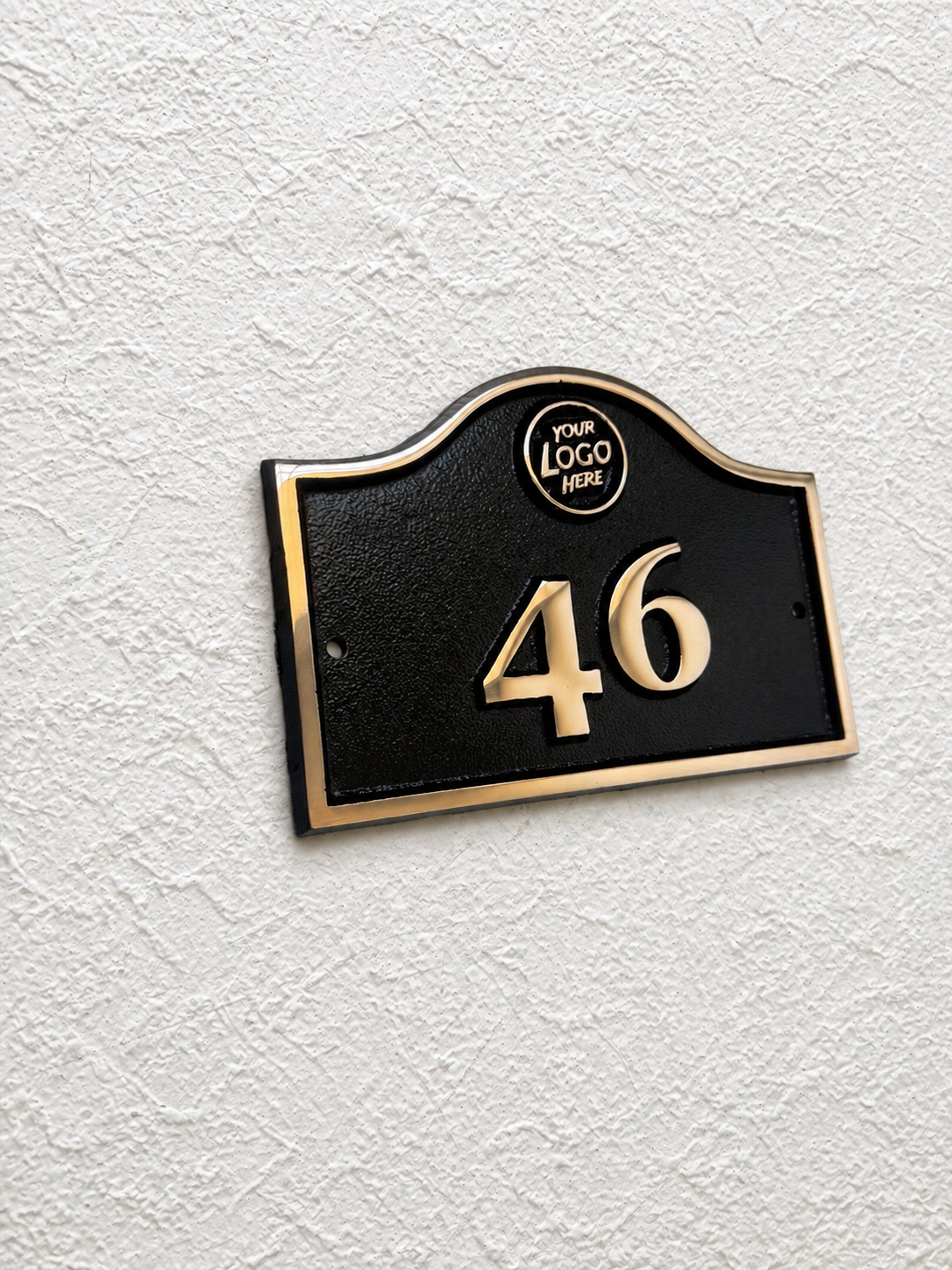 Cast bronze hotel room number sign with custom logo and raised numbers mounted on wall