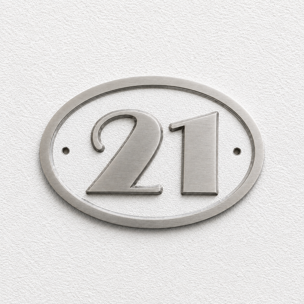 A silver oval house number plaque displaying the number 21, mounted on a textured white wall.