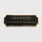 ADA Access sign with raised gold lettering on a black plaque, mounted on a textured white wall.