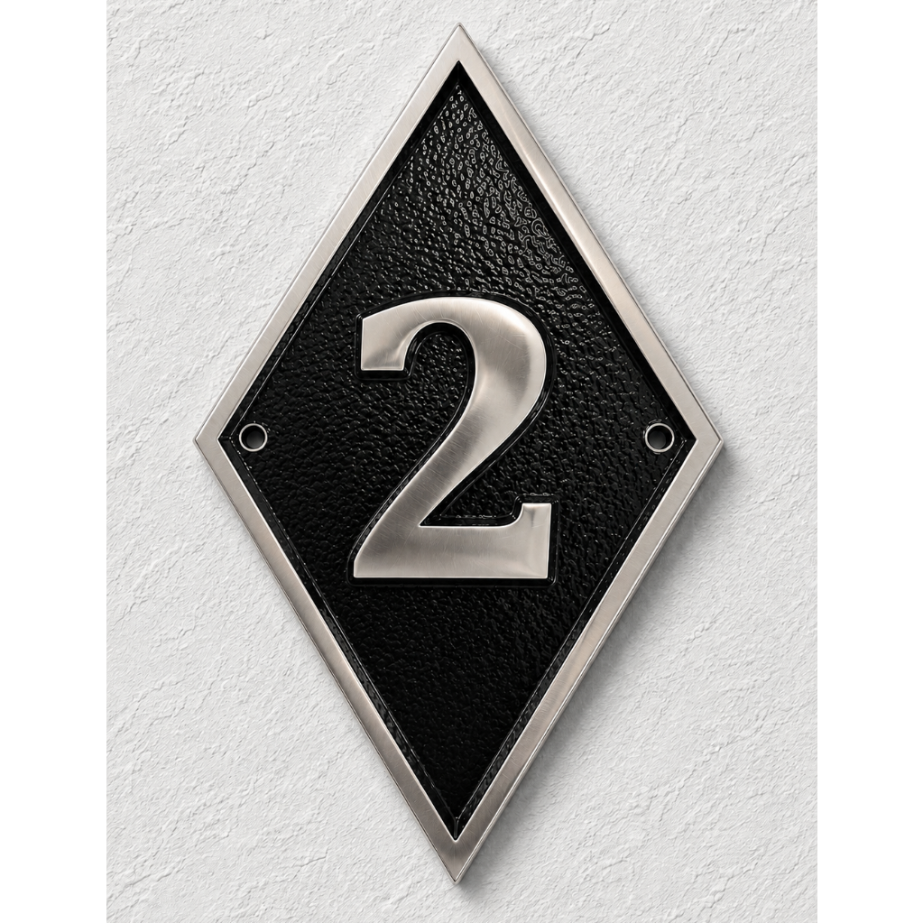 A diamond-shaped black house number plaque with a silver metallic border and the number '2' in raised silver lettering, mounted on a textured white wall.