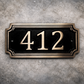 Cast bronze rectangle house number sign with raised numbers and double border mounted on exterior wall