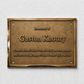 A rectangular bronze memorial plaque mounted on a textured white wall. The plaque features raised text reading 'In memory of Gaston Khoury' and a shorter inscription below, with a polished metallic border and four screw holes.