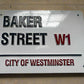 Metal sign with 'Baker Street W1' and 'City of Westminster' text on a white background