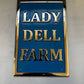 Decorative sign with 'LADY DELL FARM' text on a blue background with gold lettering.