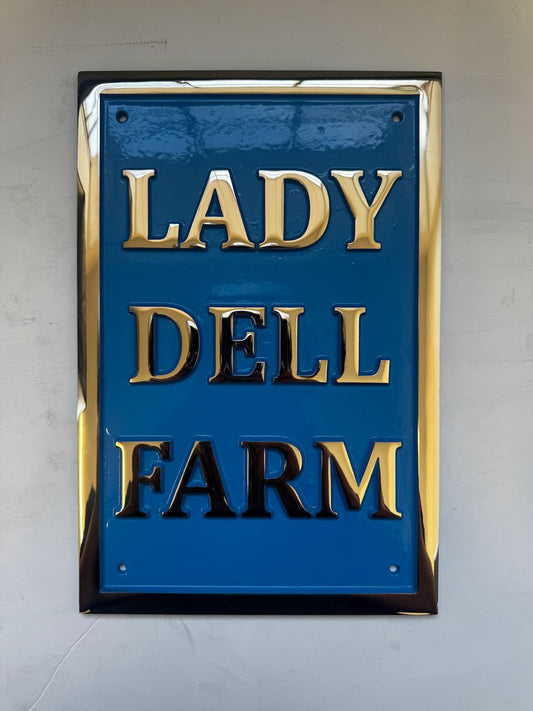 Blue sign with gold text 'LADY DELL FARM' on a blue background