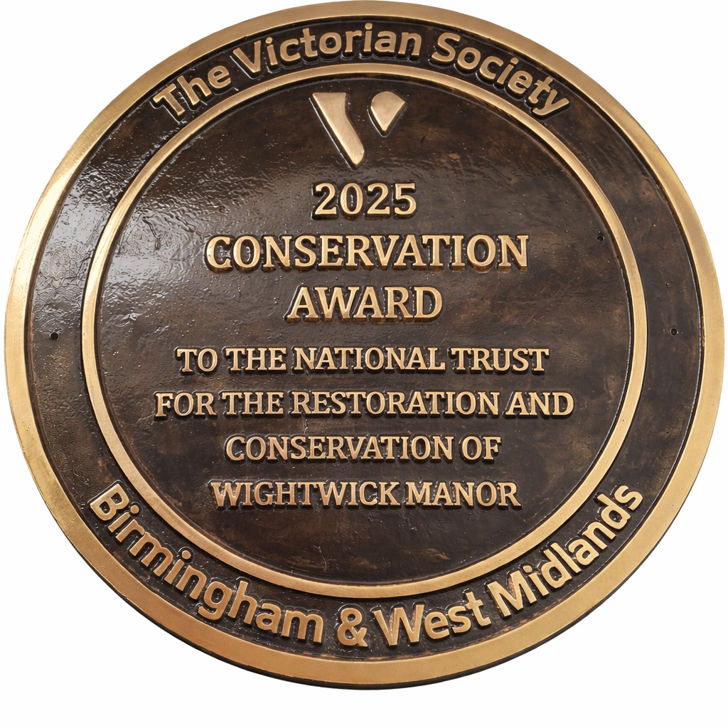 Cast bronze circular heritage plaque with raised lettering mounted on exterior wall