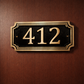 Cast bronze rectangle house number sign with raised numbers and double border mounted on exterior wall